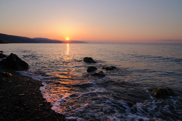 Schöne Landschaft, Sonnenuntergang am Meer, Sonne geht hinter den Bergen auf