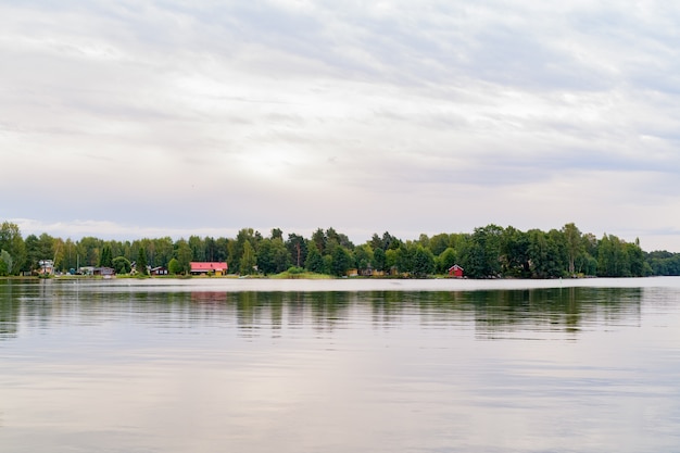Schöne Landschaftsansicht des bewölkten Himmels und des friedlichen Sees, der den Wald am Ufer reflektiert