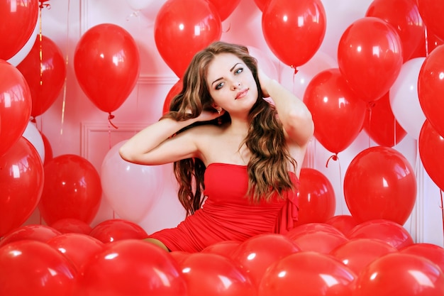 Schöne langhaarige Frau mit großen roten Luftballons