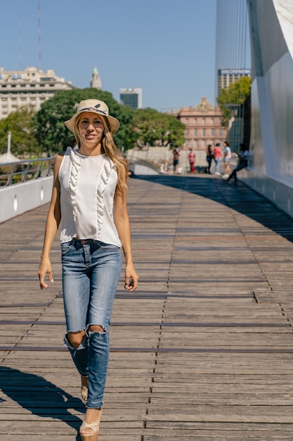 Schöne lateinische Frau, die auf einer Brücke mit einem Holzboden geht. Konzept Frauenstil.