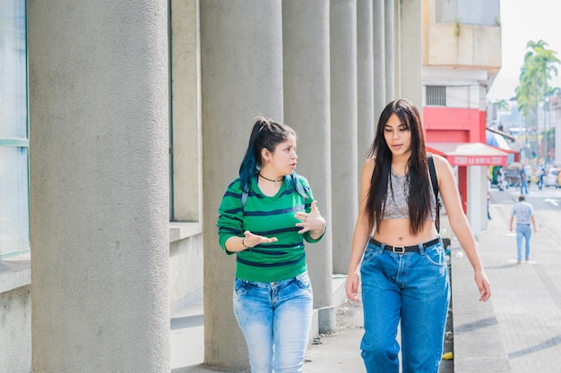 schöne latina-mädchen, kaukasisch und brünett, die die straße hinuntergehen und über ihr studium sprechen