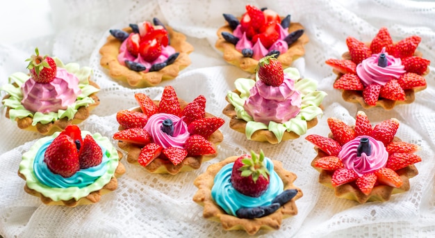 Schöne leckere Cupcakes hautnah mit Erdbeeren, Geißblatt, blauer und rosa Creme