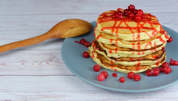 schöne leckere Punkcakes mit Erdbeersauce und Beeren der Johannisbeere auf einem hölzernen Hintergrund