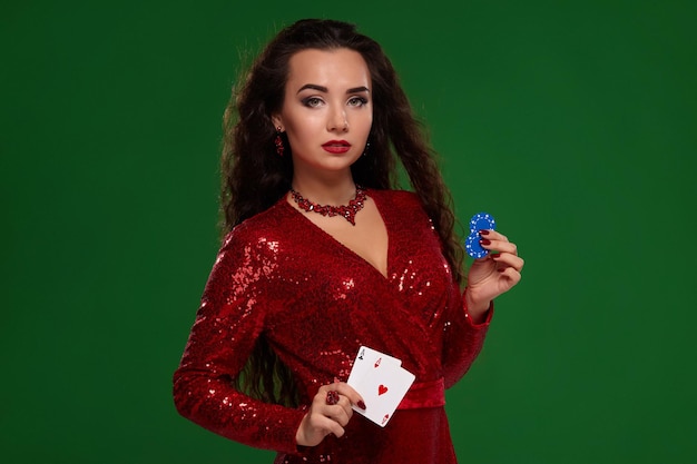 Schöne lockige Frau in einem glitzernden Kleid mit einigen Spielkarten und Spielchips Casino