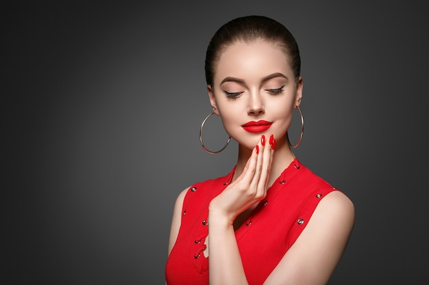 Schöne lockige Haarfrau in Rot mit roten Lippen und Kleidermaniküre, Schönheitsrote Afrofrisur. Studioaufnahme.