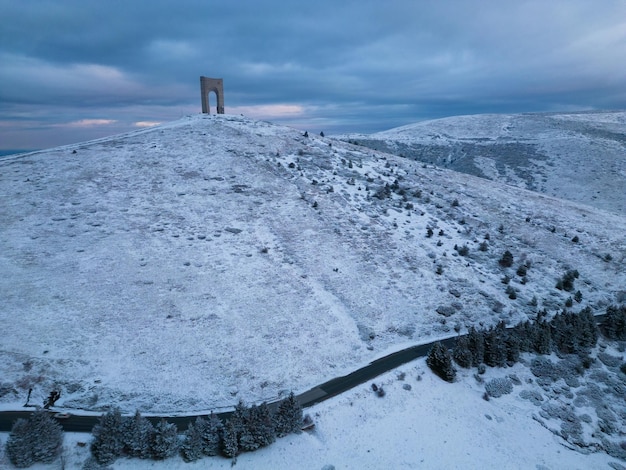 Schöne Luftaufnahme der schneebedeckten Berge und des Monument Arch of Liberty am Hauptkamm des Balkangebirges Bulgarien am Wintermorgen