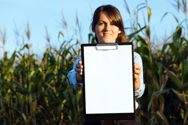 Schöne Mädchen-Agronomin mit Notizbuch und analysiert die Maisernte