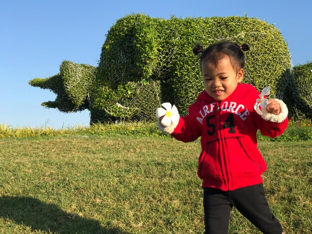 Foto schöne mädchen hält blumen, während sie im öffentlichen park auf dem gras spazieren geht