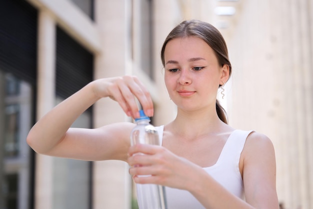 schöne Mädchen junge durstige Frau trinkt reines frisches Wasser aus der Flaschenöffnung am Sommertag