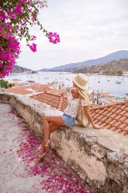 Schöne Mädchentouristin steht auf einer Straße mit Blick auf das Meer und die Bucht Poros Griechenland