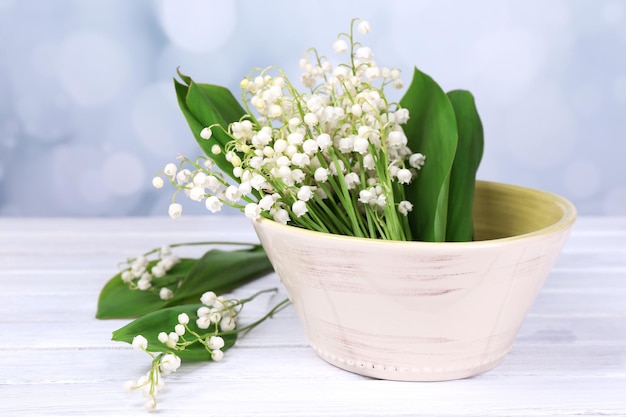 Foto schöne maiglöckchen in vase auf holztisch