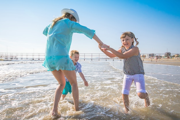 Schöne Mama spielt mit ihren Kindern im Meer