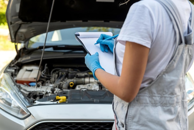 Schöne Mechanikerin arbeitet an einer Autopanne in einer Autowerkstatt