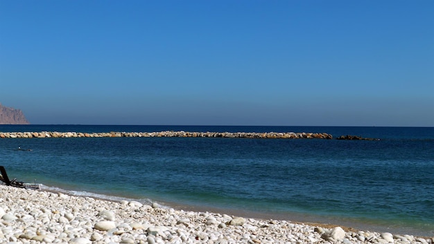 Schöne Meereslandschaft, klares blaues Meer, Kiesstrand, Berge in der Ferne, mediterranes Spanien