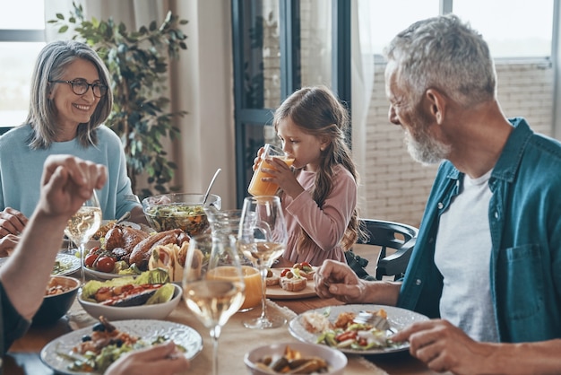 Schöne Mehrgenerationenfamilie, die beim gemeinsamen Abendessen kommuniziert und lächelt