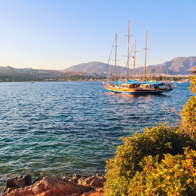 Schöne Mittelmeerküste mit Inselbergen und Yacht bei Sonnenuntergang