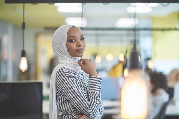 Schöne moderne afrikanische muslimische Geschäftsfrau im Büro, die Hijab im kreativen modernen Startup-Coworking Space trägt