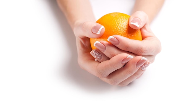 Schöne moderne Maniküre Weibliche Hände halten eine Orange