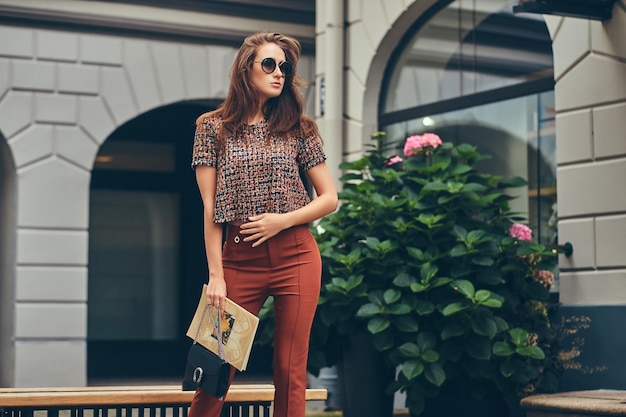 Schöne modische Brünette mit trendiger Kleidung und Sonnenbrille.