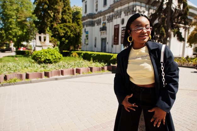 Schöne modische junge Afroamerikanerfrau, die gegen katholische Kathedralen-Sonnenbrille-Gelboberseite aufwirft Modesommerfoto Helle Farben Schöne Aussicht Afro-Leute