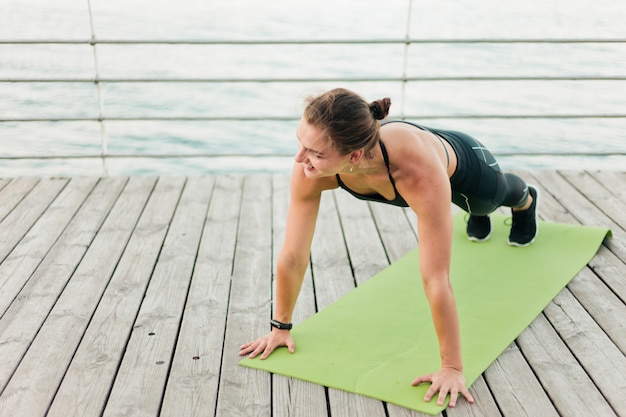 Schöne muskulöse Sportlerin in Sportswear Leistung ihren Körper Liegestütze von der Strandterrasse. Outdoor-Sportarten