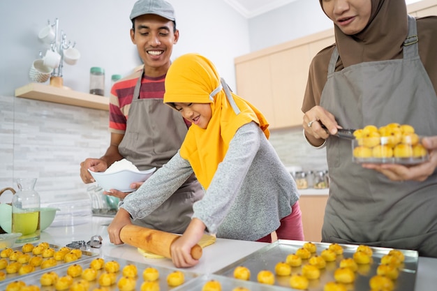 Schöne muslimische Familie, die zusammen zu Hause Nastar-Ananaskuchen der indonesischen Tradition macht