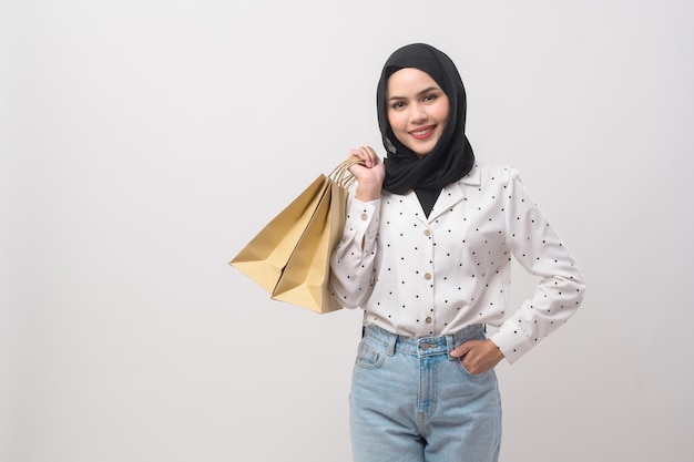 Schöne muslimische Frau mit Hijab, Kreditkarte und Einkaufstasche in der Hand