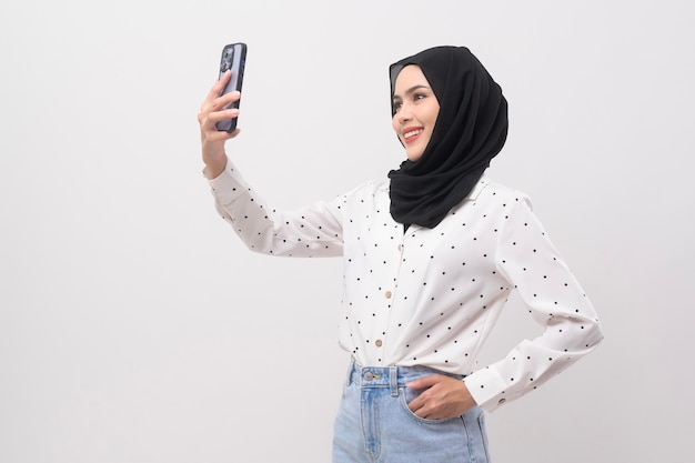 Schöne muslimische Frau mit Hijab mit Smartphone über weißem Hintergrund Technologiekonzept x9x9