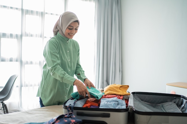 Schöne muslimische Frauen, die Koffer vorbereiten