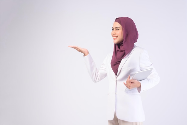 Schöne muslimische Geschäftsfrau im weißen Anzug mit Hijab mit Tablet in studiox9