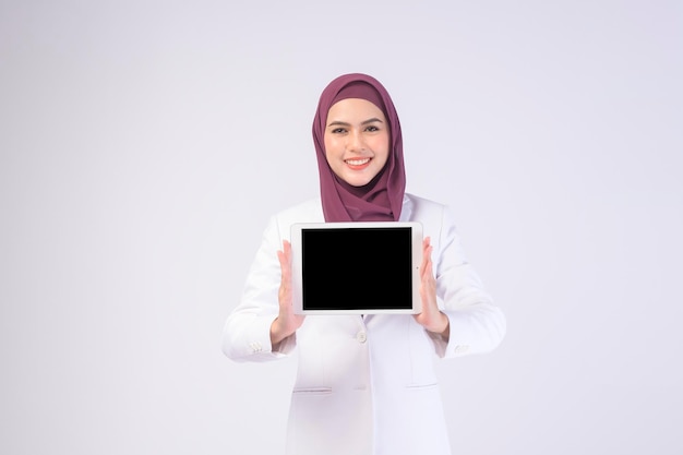 Schöne muslimische Geschäftsfrau im weißen Anzug mit Hijab mit Tablet in studiox9