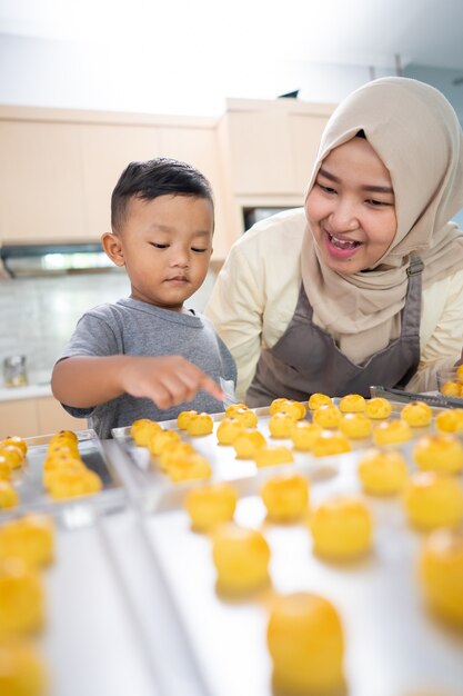 Schöne muslimische Mutter, die mit ihrem Sohn zu Hause zusammen Kuchen für Eid Mubarak macht