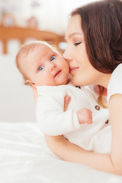 Schöne Mutter, die ihre kleine Babytochter küsst