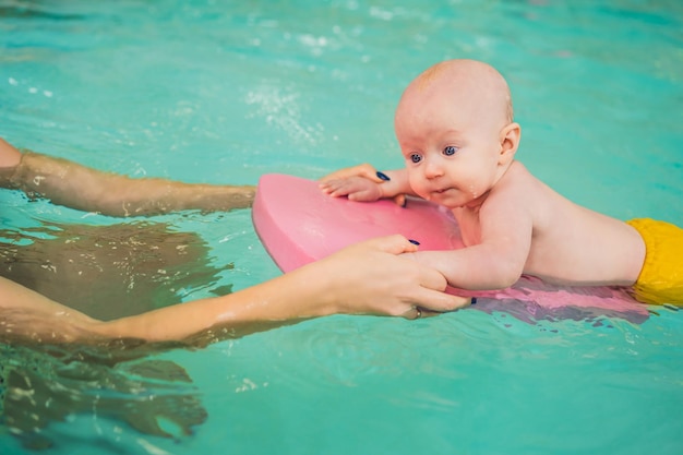 Schöne Mutter, die niedlichem Babymädchen beibringt, wie man in einem Schwimmbad schwimmt Kind, das Spaß im Wasser mit Mutter hat