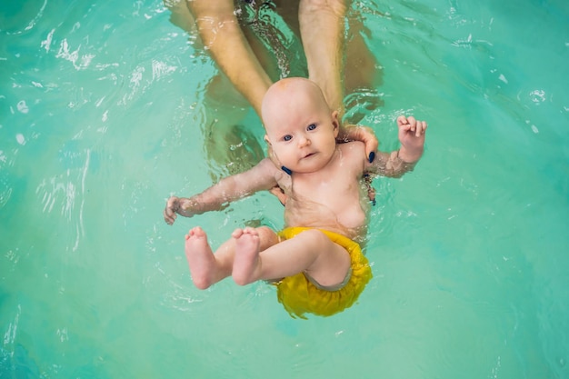 Schöne Mutter, die niedlichem Babymädchen beibringt, wie man in einem Schwimmbad schwimmt Kind, das Spaß im Wasser mit Mutter hat