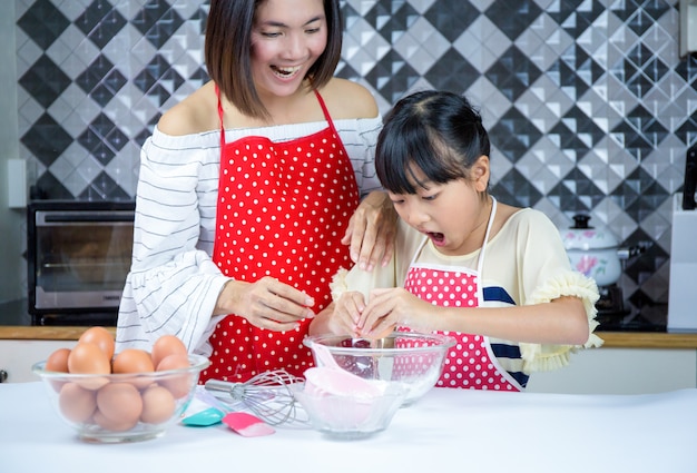 schöne Mutter lehrt Tochter Teig in der Küche zubereiten. Konzept Familie glücklich.