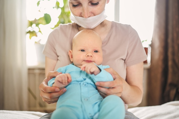 Schöne Mutter mit einer Maske mit ihrem Baby