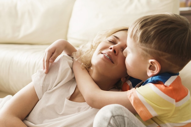 Schöne Mutter und ihr süßer Sohn in der Umarmung zu Hause