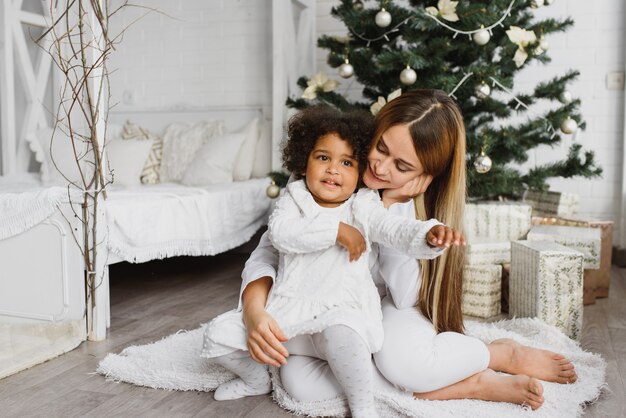 Schöne Mutter und ihre Tochter in der Nähe des Weihnachtsbaumes