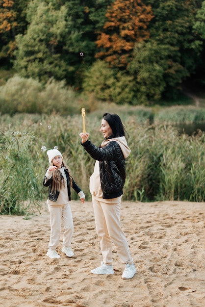 Schöne Mutter und Tochter haben gemeinsam Spaß im Herbstpark im Sand