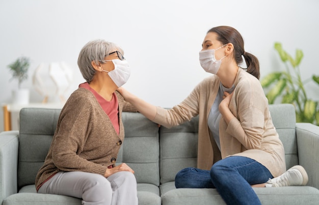 Schöne Mutter und Tochter sprechen und lächeln, während sie zu Hause auf der Couch sitzen