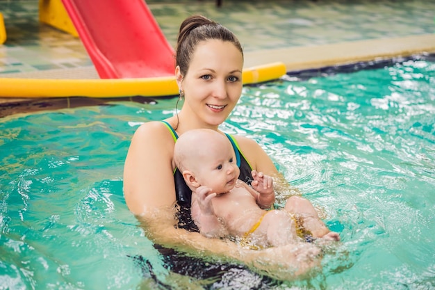 Foto schöne mutter unterrichtet ein süßes baby, wie man im schwimmbad schwimmt.