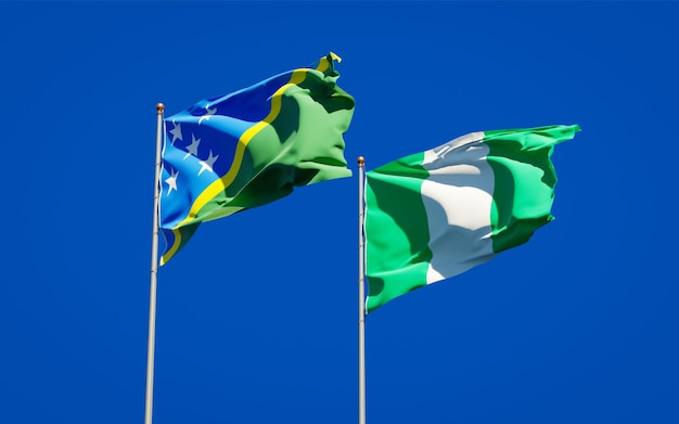 Schöne Nationalstaatsflaggen der Salomonen und Nigerias zusammen auf blauem Himmel