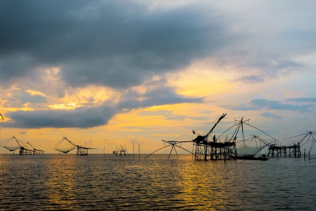 Schöne Naturlandschaft des Songkhla-Sees bei Sonnenaufgang und Fischer verwenden Bambus und Netz als einheimisches Angelwerkzeug, um Fische im ländlichen Lebensstil am Pakpra-Kanal, Baan Pak Pra, Phatthalung, Thailand zu fangen