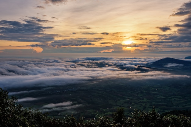 Schöne Naturlandschaft die Sonne ist über dem Meeresnebel, der die Berge und den hellen Himmel während des Sonnenaufgangs im Winter am Aussichtspunkt des Nationalparks Phu Ruea, Provinz Loei, Thailand bedeckt.