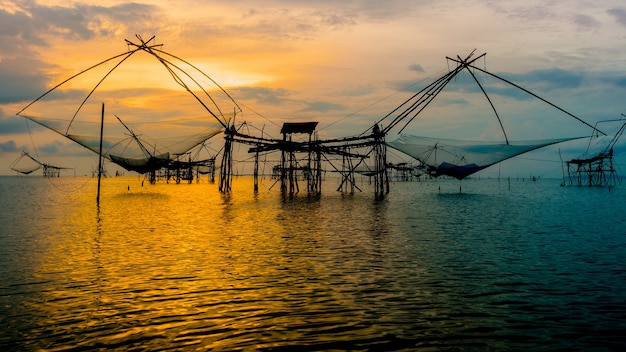 Schöne Naturlandschaft goldenes Licht des Morgenhimmels bei Sonnenaufgang und einheimischer Fischfangwerkzeug ländlicher Lebensstil am Pakpra-Kanal im Songkhla-See, Baan Pak Pra, Phatthalung, Thailand, 16: 9 Breitbild