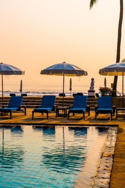 Foto schöne palme mit sonnenschirmstuhlpool im luxushotelresort bei sonnenaufgang