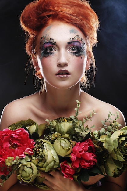 Schöne redhair Frau, die Blumen hält
