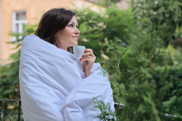 Schöne reife Frau, die mit Tasse Kaffee entspannt