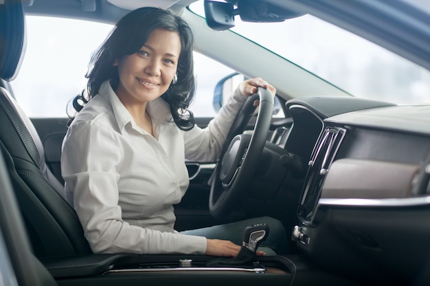 Foto schöne reife frau, die neue autos am autohaus auscheckt